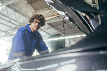 Mechanic man checking and repairing car radiator bonnet in automotive in garage at auto repair shop, motor technician working after vehicle service maintenance concept