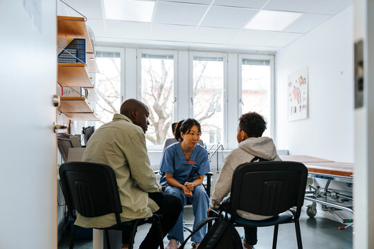 Female medical professional sitting with father and son in examination room