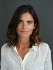 Fototapeta premium Portrait of Woman with Brown Hair in White Shirt Against Dark Background