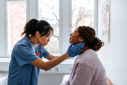 Focused female medical expert checking lymph nodes of young patient in examination room at hospital