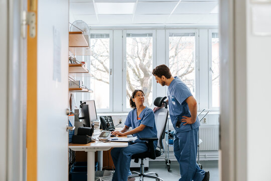 Female doctor talking with male colleague standing by in examination room at hospital