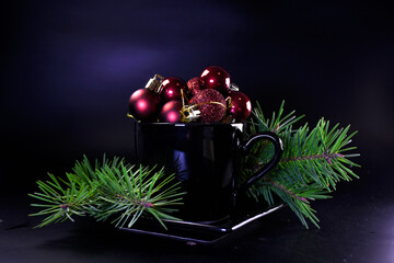Christmas tree branches with fresh lingonberries on a black background. Black cup with coffee and...