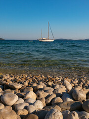 Adriatic Sea with boat on blue sea and round rocks below