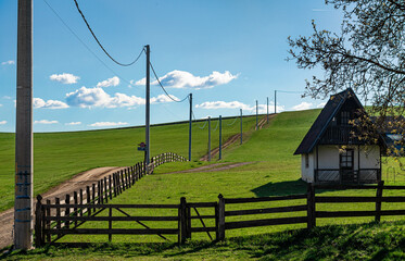Green grass farm with a small wooden house and rural road