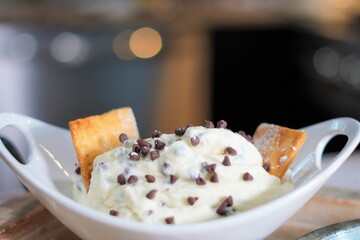 A delicious bowl of creamy and sweet cannoli dip with milk chocolate mini chips.  Dessert dip with cannoli chips, mini chocolate chips and creamy cannoli filling.