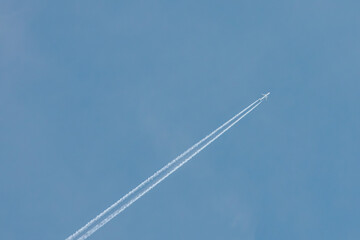 A jet airplane flying at high altitude, leaving a clean, straight contrail across the clear blue sky. The minimalist scene evokes freedom and simplicity in open airspace.