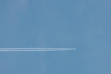 A jet airplane flying at high altitude, leaving a clean, straight contrail across the clear blue sky. The minimalist scene evokes freedom and simplicity in open airspace.