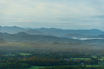 Obraz premium Dramatic sunset over mountain landscape. Beautiful landscape foggy hills twilight time. Blue golden sky sunrise dramatic beautiful landscape mountain. Dawn sky gold dusk time cloudscape with sunlight