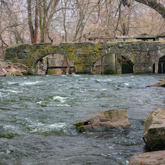 Stone bridge - a fragment of a mill. The flow of a rapid river rushed into a mill wheel.Water wheel...