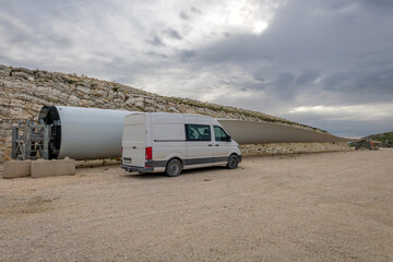 A rotor blade of a wind turbine on the ground along side a van, showing the actual size and scale...