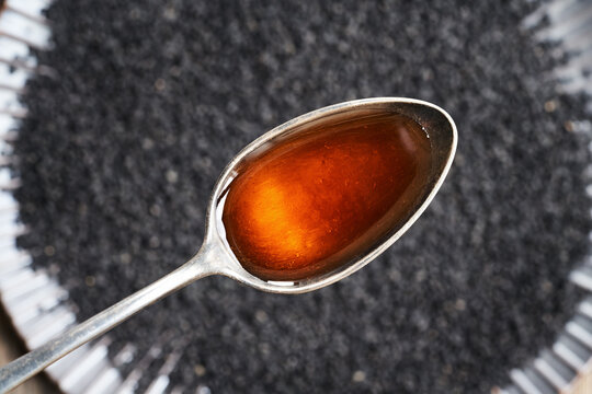 Black cumin or Nigella sativa seed oil on a spoon. Healthy anti-inflammatory and antioxidant supplement.