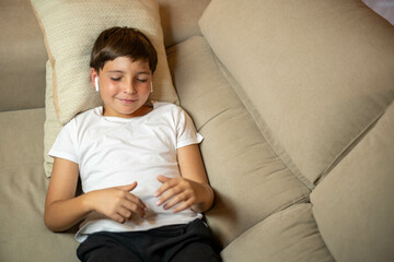 Music and relaxation: child relaxes on the sofa listening to his favorite songs