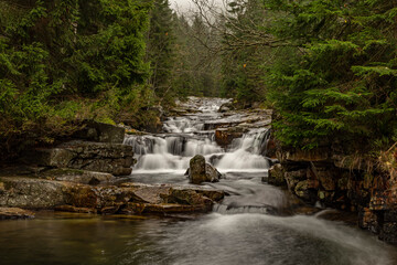 landscape in Krkonose with waterfall between trees and rocks on autumntime