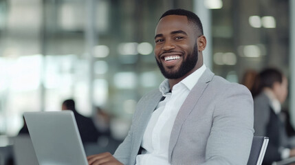 A man with a big smile is sitting in front of a laptop