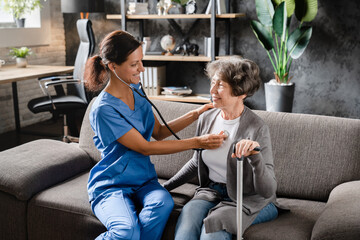 Nurse doctor caregiver listening to the patient`s chest heart lungs with stethoscope....