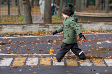 A little boy of 5 years old crosses the street at a pedestrian crossing. Traffic Laws. Be...