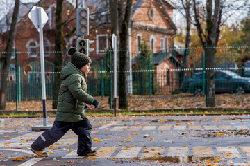 A little boy of 5 years old crosses the street at a pedestrian crossing. Traffic Laws. Be...