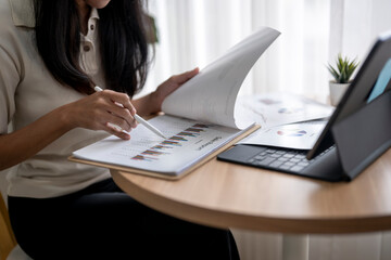 Businesswoman analyzing financial chart using digital tablet and documents at work
