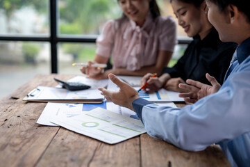 A group of people are sitting around a table with papers and calculators