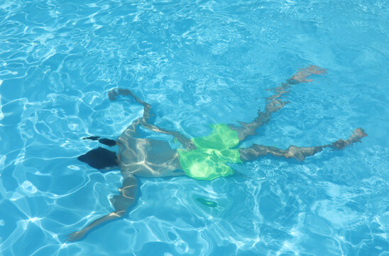 person who looks drowned at the bottom of the pool wearing a swimsuit with blue water