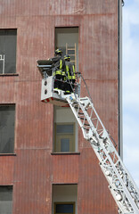 firefighters on the long ladder truck in the metal basket during an emergency operation
