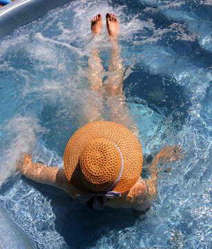 woman relaxes in a hot tub wearing a straw hat at a spa resort