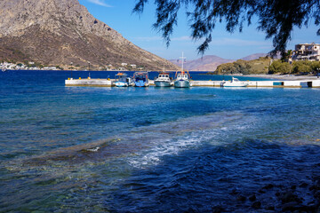 Boats anchored at the pier in Kalymnos. View over the Aegean Sea, Greek island landscape with mountains, blue sky