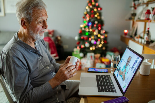 Senior man video calling doctor while holding medication at home
