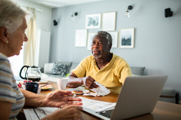 Senior couple discussing bills at kitchen table