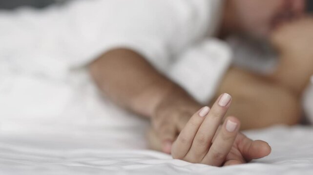 Sensual couple in bed enjoying privacy with each other.  Focus on the hands of the man and woman.