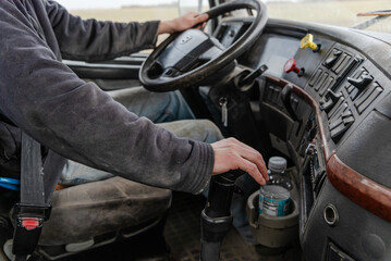Interior View of an Old Semi Truck Dashboard: Dusty Controls for Air Brakes, Cruise Control, with Keys in the Ignition, as Farmer Shifts Gears on a Rural Dirt Road with Crops Out window