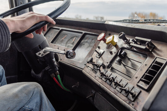 Interior View of an Old Semi Truck Dashboard: Dusty Controls for Air Brakes, Cruise Control, with Keys in the Ignition, as Farmer Shifts Gears on a Rural Dirt Road with Crops Out window