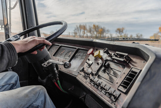 Interior View of an Old Semi Truck Dashboard: Dusty Controls for Air Brakes, Cruise Control, with Keys in the Ignition, as Farmer Shifts Gears on a Rural Dirt Road with Crops Out window