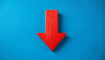Red wooden arrow pointing down on blue background. Business, market decline or economic