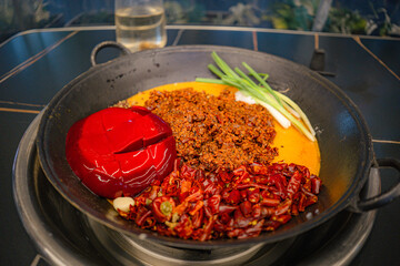 Table top view of Mala seasoning spicy Chinese hotpot. Hotpot is an interactive meal in which diners sit around a simmering pot of soup at the center of the table with ingredients.