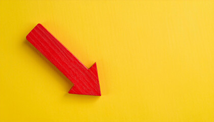 Obraz premium Red wooden arrow pointing down on yellow background. Business, market decline or economic