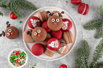 Beautiful Christmas chocolate and raspberry macarons on a plate on a concrete background. Festive dessert. Top view, copy space.