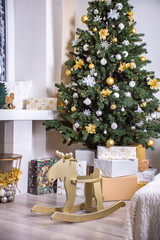 Christmas tree is decorated with gold and silver toys and gifts in a white classic interior. Christmas tree at home. Christmas tree decoration.