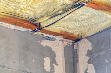 View of ceiling of building with insulation pipes running through it. Foam insulation. Construction.