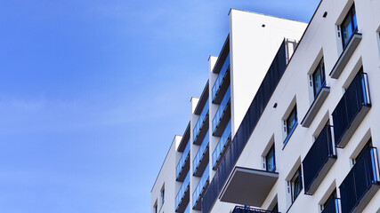 Modern high-rise apartment building  in white, stand tall against a blue sky, exemplifying...