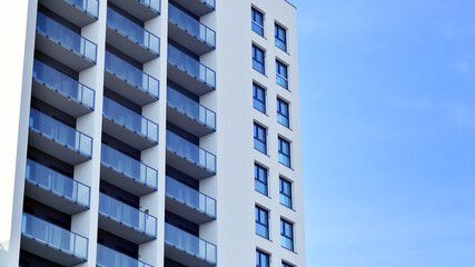 Modern high-rise apartment building  in white, stand tall against a blue sky, exemplifying innovative urban architecture with sleek, angular designs.