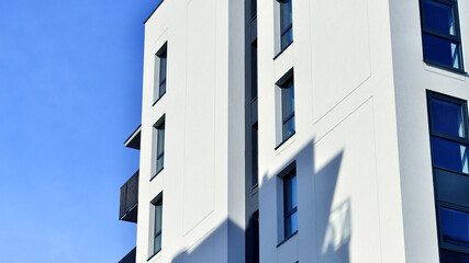 Modern high-rise apartment building  in white, stand tall against a blue sky, exemplifying...