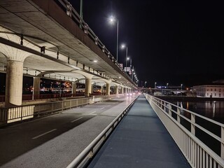 A nighttime view of an illuminated bridge with symmetrical streetlights and pathways