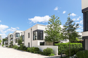 Residential area with ecological and sustainable green residential buildings, low-energy detached houses with white facade and flat roof, timber construction and green courtyard