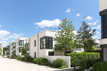 Residential area with ecological and sustainable green residential buildings, low-energy detached houses with white facade and flat roof, timber construction and green courtyard