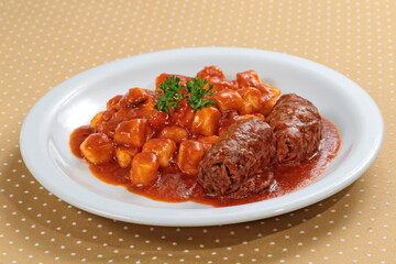gnocchi with braciola in tomato sauce on plate