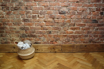 Cozy Basket of Throws Against Exposed Brick Wall and Wood Floor, Minimalist Interior Background