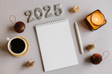 Goals 2025 concept. New Year Routine. Empty notebook, pen, cup of coffee, burning candle and paper honeycomb baubles. Flat lay style