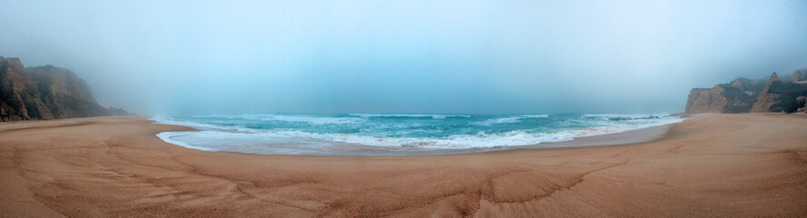 A serene, foggy beach scene with gentle waves rolling onto the s