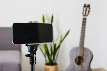 Online guitar lessons. Smartphone and guitar in a bright room. Selective focus